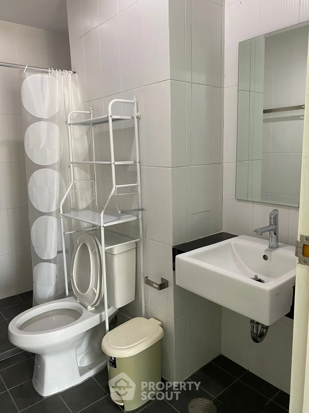 Modern bathroom with sleek fixtures and white tiles, featuring a compact sink and toilet.