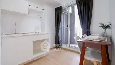 Modern kitchen with open layout and balcony access, featuring sleek white cabinetry and elegant dining area.