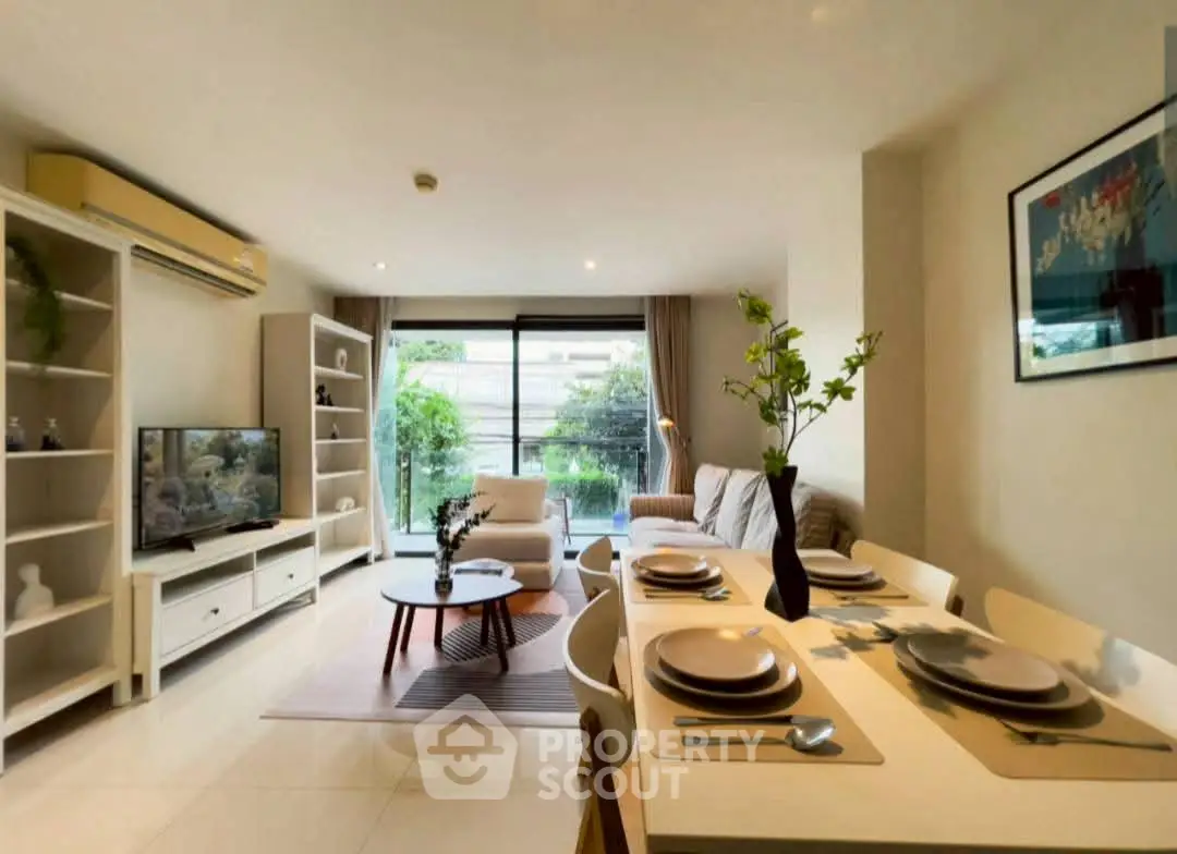 Spacious living room with modern decor and dining area, featuring large windows and greenery view.