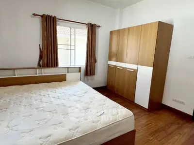 Spacious bedroom with wooden wardrobe and large window for natural light.