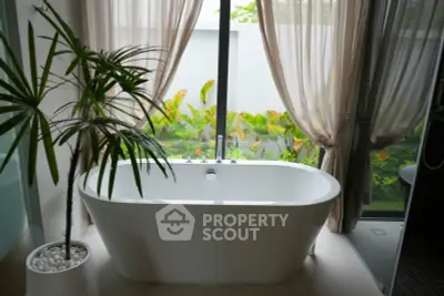 Luxurious bathroom with freestanding bathtub and garden view, perfect for relaxation.