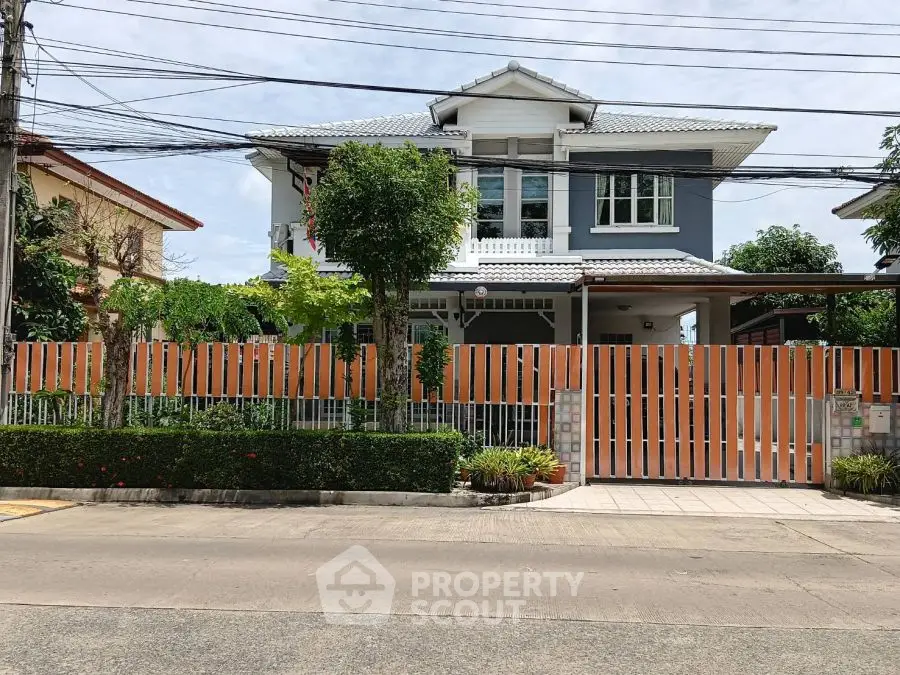 Charming two-story house with a spacious front yard and modern fence.