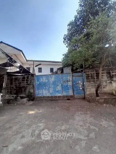 Secure gated entrance to residential property with blue metal gate and surrounding walls.
