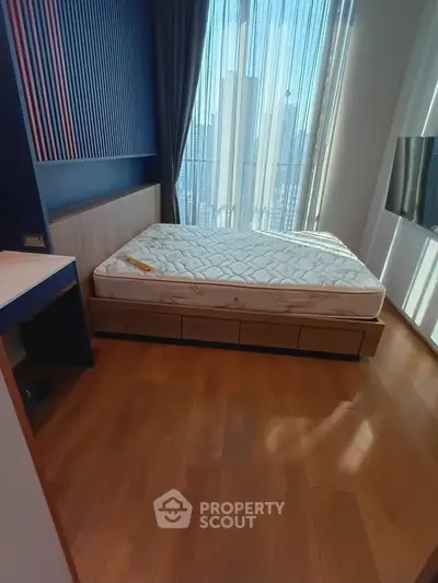 Modern bedroom with large window and natural light, featuring a comfortable bed and sleek wooden flooring.