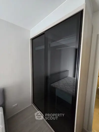 Modern bedroom with sleek black sliding wardrobe and minimalist design.