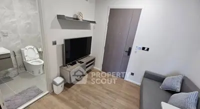 Compact modern living room with TV and adjacent bathroom, featuring sleek design and cozy atmosphere.