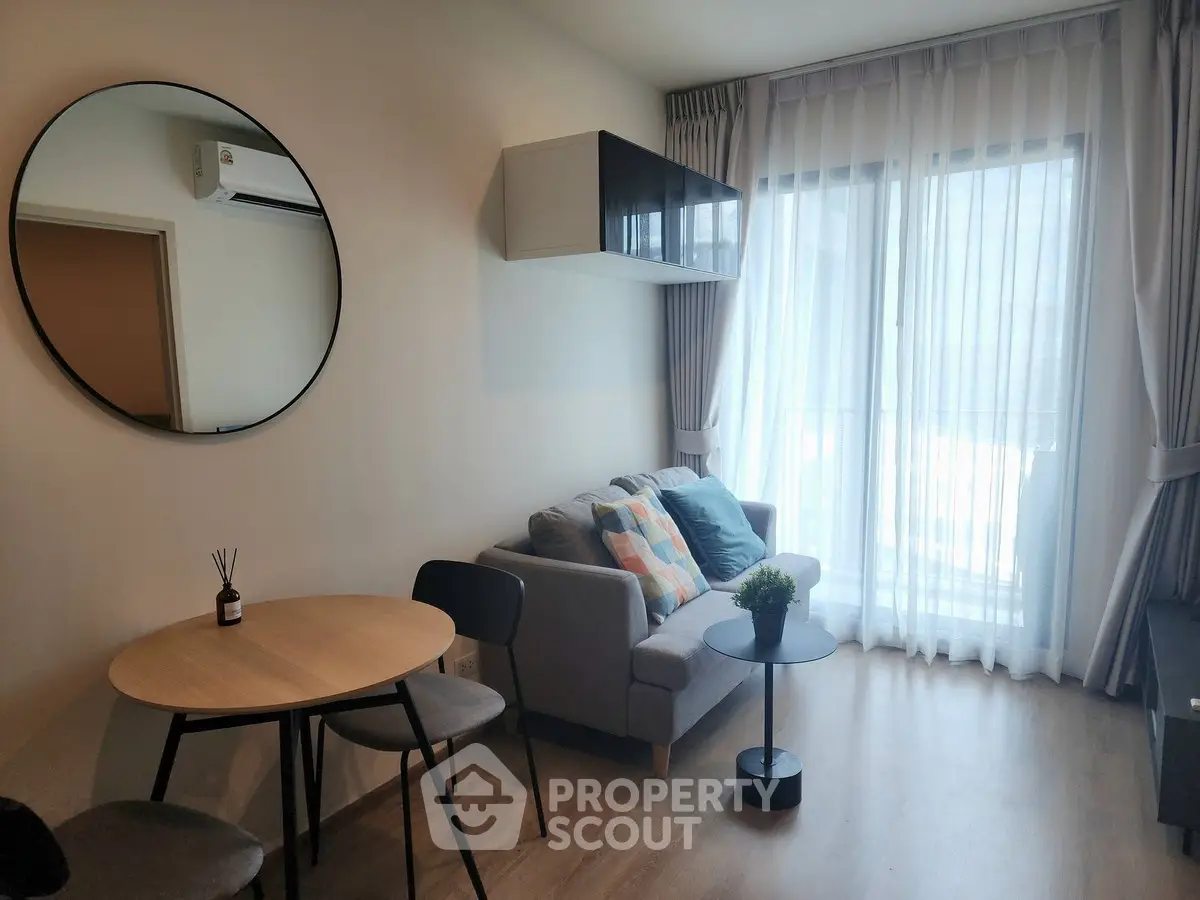 Modern living room with stylish decor and natural light, featuring a cozy sofa and dining area.