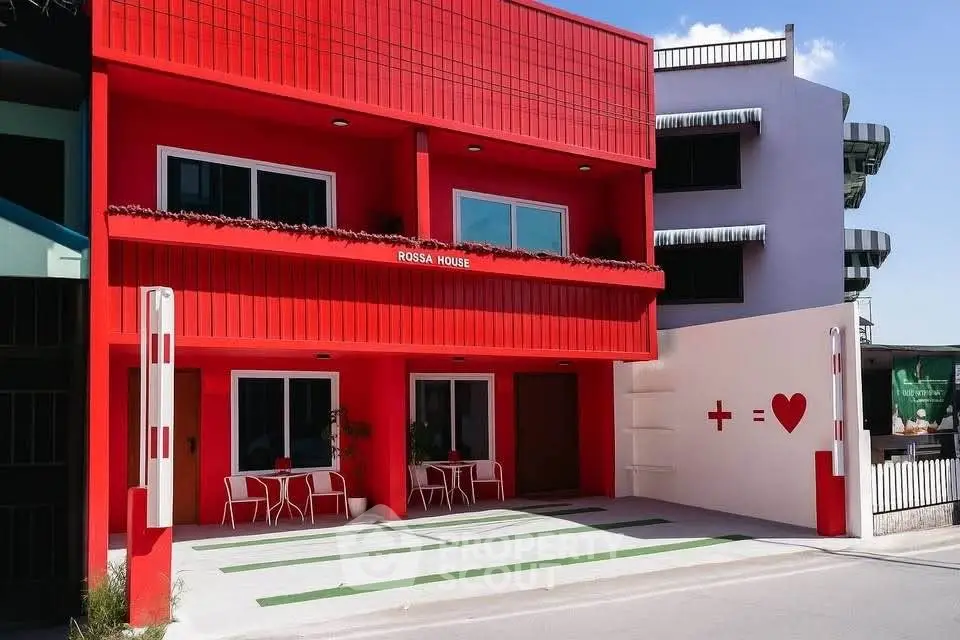 Vibrant red modern building exterior with unique design and artistic wall art, perfect for creative urban living.