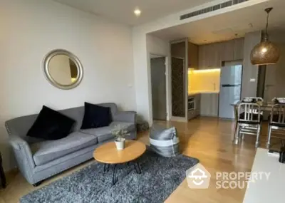 Elegant living room seamlessly connects to a modern kitchen, featuring plush sofa, chic coffee table, and ambient lighting.