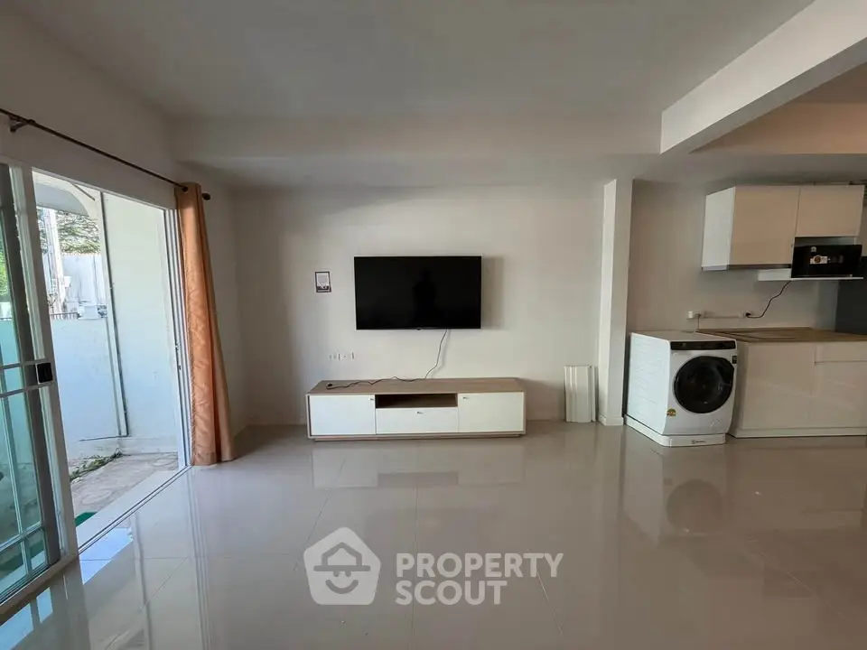 Modern living room with wall-mounted TV and washing machine, open layout design.
