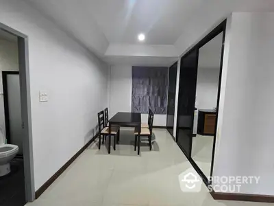 Modern dining area with sleek table and chairs, adjacent to a glass partition and minimalist decor.