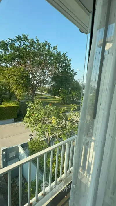 Charming balcony view with lush greenery and clear blue sky, perfect for relaxation.