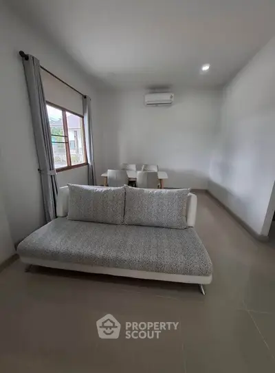 Modern living room with sleek sofa and dining area, featuring neutral tones and ample natural light.