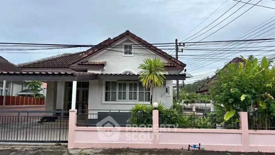 Charming single-story house with tiled roof and lush garden in serene neighborhood.