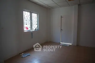 Spacious empty room with tiled floor and window, ready for customization.