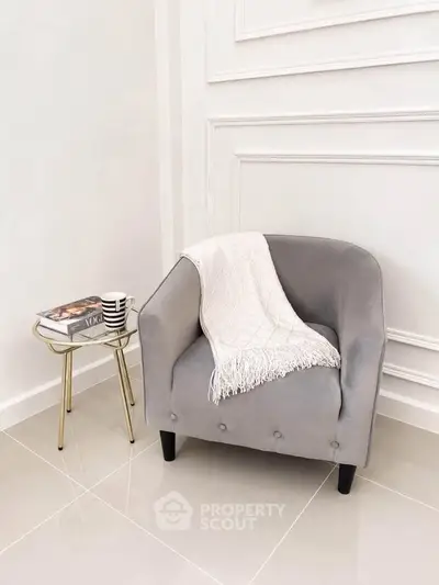 Elegant corner with a plush gray armchair and chic side table in a modern interior.