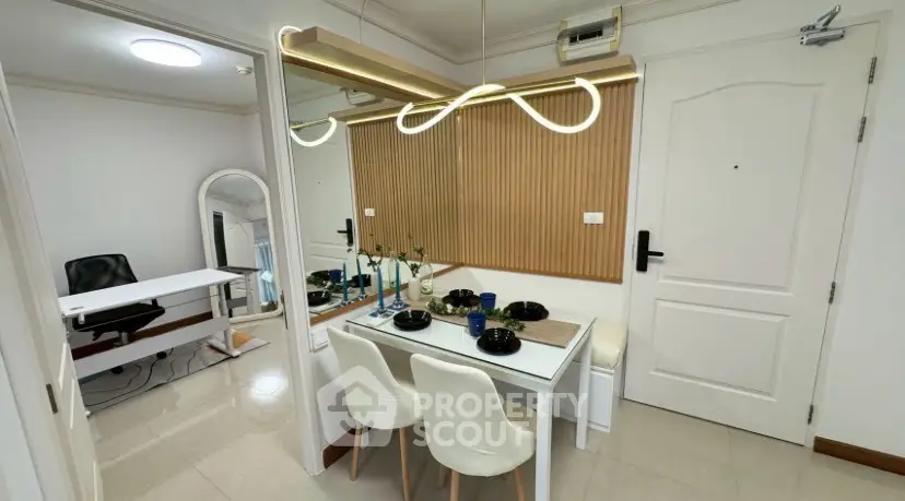 Modern dining area with stylish lighting and mirror, adjacent to a home office space.