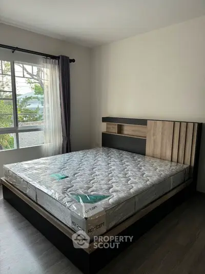 Modern bedroom with large window and stylish bed frame in a bright, airy space.