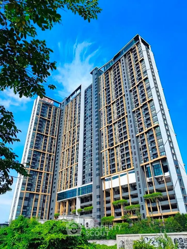 Stunning modern high-rise building with lush greenery and clear blue sky