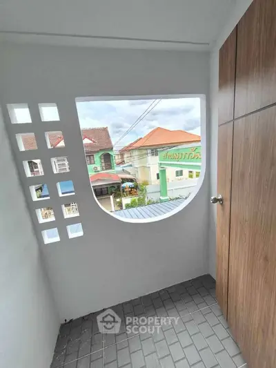 Charming balcony with unique window design and scenic neighborhood view, perfect for relaxation and enjoying the outdoors.
