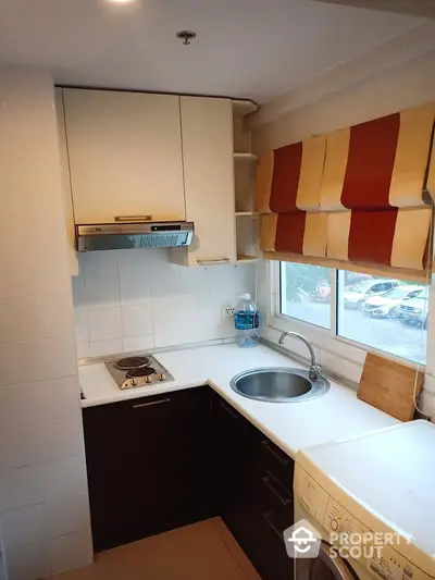 Cozy kitchen with corner layout, electric stove, and washing machine under window.