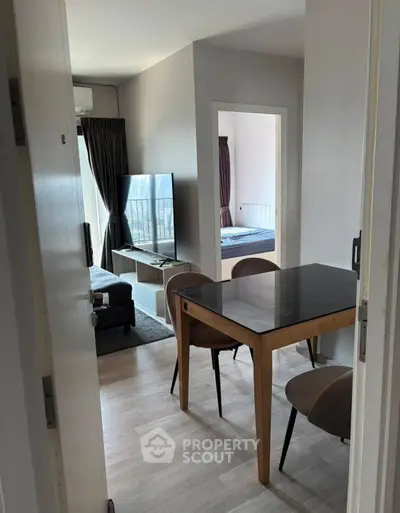 Modern apartment interior with dining area and living room, featuring sleek furniture and natural light.