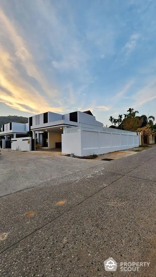 Modern white house exterior with spacious driveway and scenic sky view