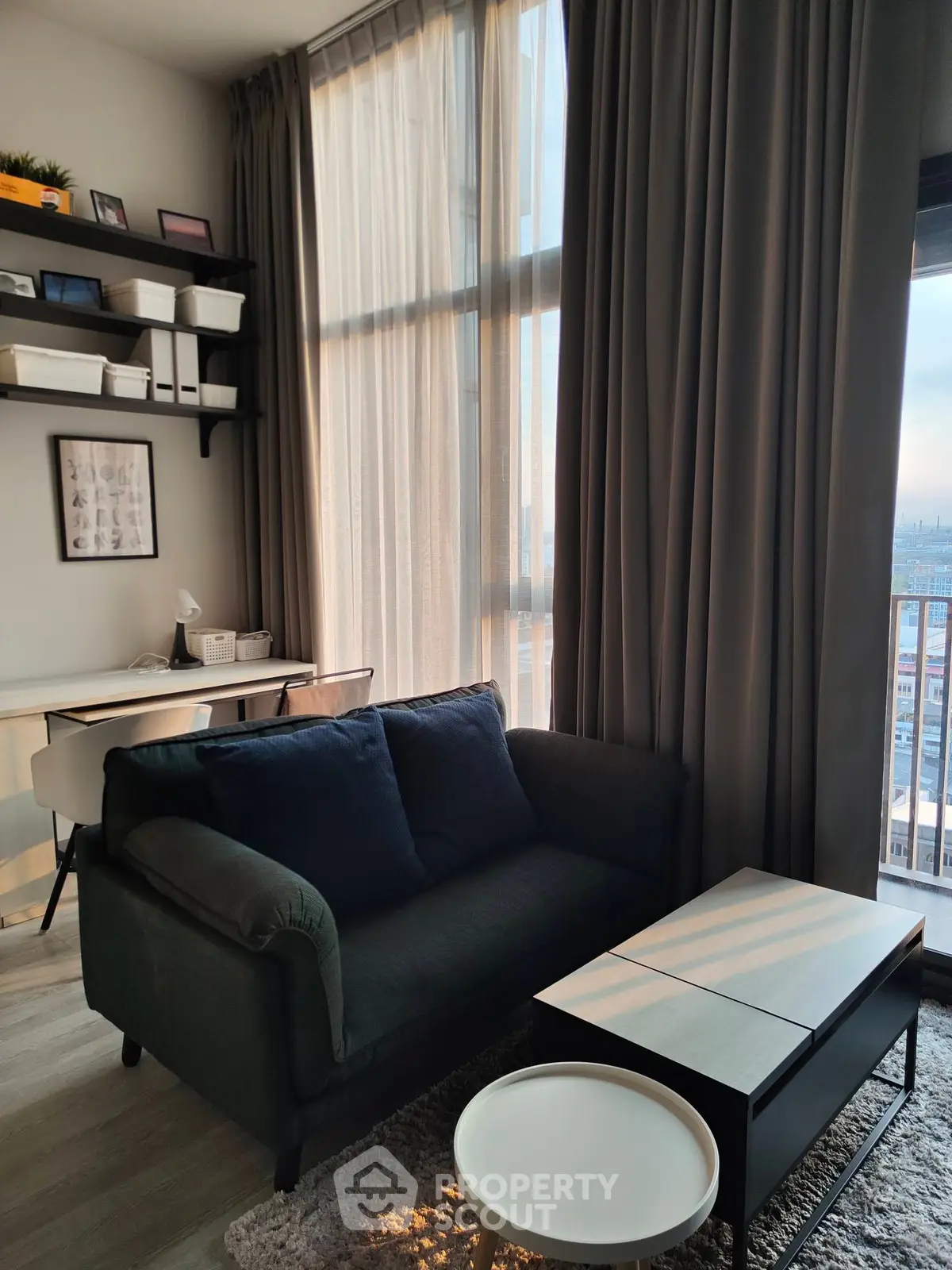 Modern living room with high ceilings, large windows, and stylish furniture in a city apartment.