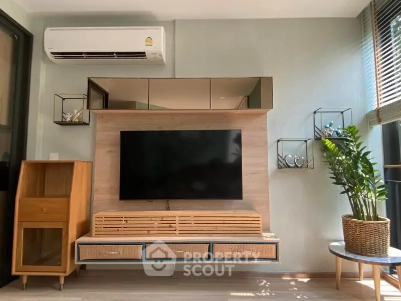 Modern living room with stylish TV unit and air conditioning, featuring natural light and contemporary decor.