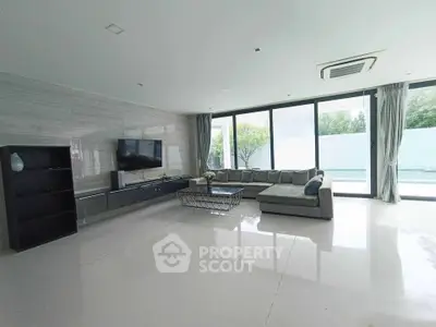 Spacious modern living room with large windows and pool view, perfect for relaxation and entertainment.
