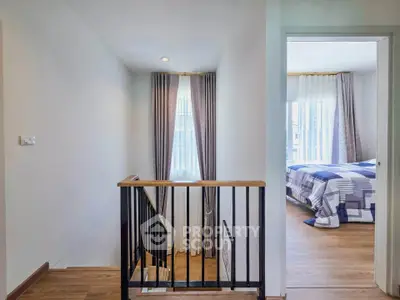 Bright and airy hallway leading to a cozy bedroom with modern decor and wooden flooring.