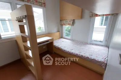 Cozy bedroom with built-in desk and ample natural light from large windows.