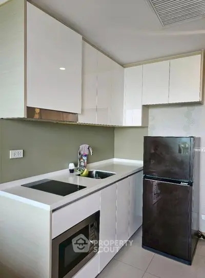Modern kitchen with sleek cabinetry, built-in appliances, and compact fridge in a stylish apartment.