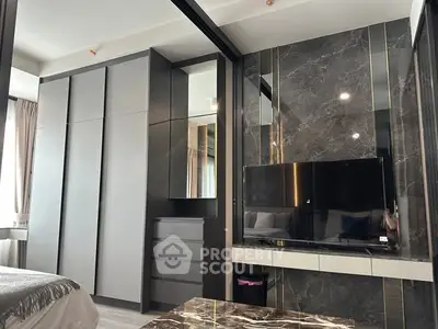 Modern bedroom with sleek wardrobe and marble accent wall featuring a flat-screen TV.