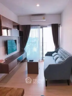 Modern living room with stylish sofa and wall-mounted TV in a bright apartment.