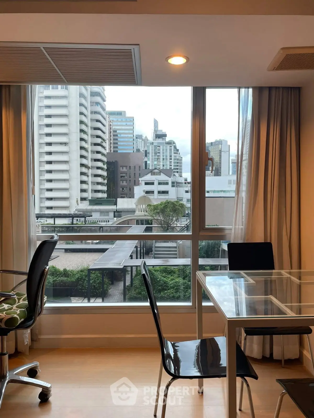 Modern apartment with city view, featuring glass dining table and sleek chairs, perfect for urban living.