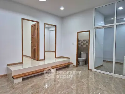 Spacious interior with modern design featuring a unique elevated platform and sleek tiled flooring.