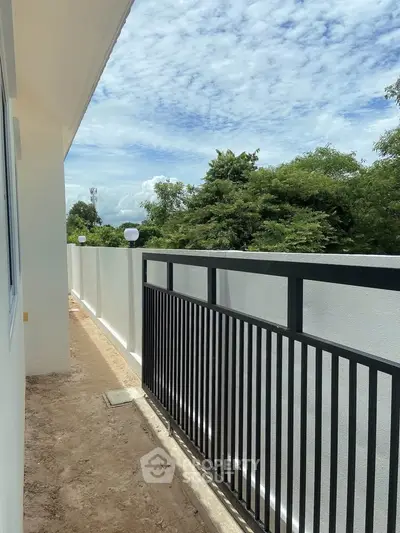 Spacious balcony with modern railing and lush green view, perfect for relaxation.