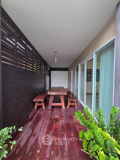 Charming wooden deck with seating area and lush greenery, perfect for outdoor relaxation.