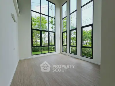 Spacious room with floor-to-ceiling windows offering lush garden views, perfect for modern living.