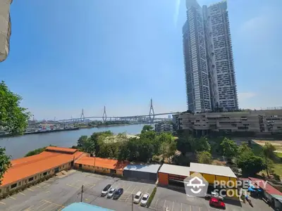 Stunning river view from high-rise building with modern architecture and clear blue sky.