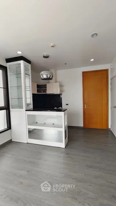 Modern apartment interior with sleek kitchen and wooden door, featuring open layout and stylish flooring.