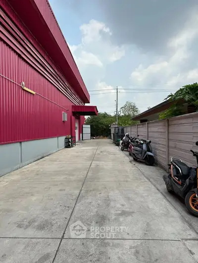 Spacious industrial property with vibrant red exterior and ample parking space.