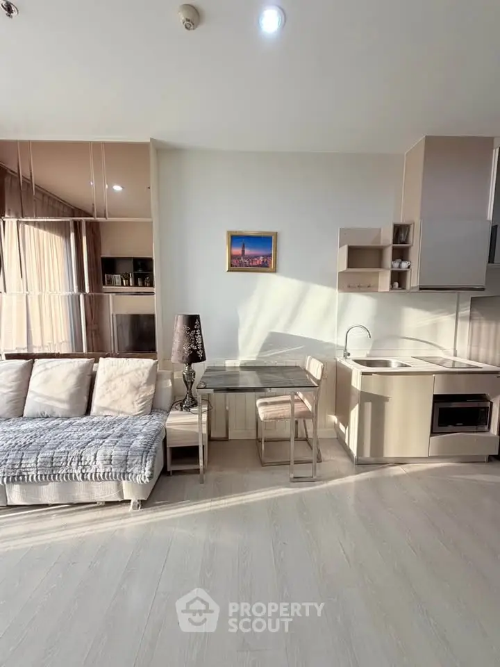 Modern living room with open kitchen, stylish decor, and ample natural light.