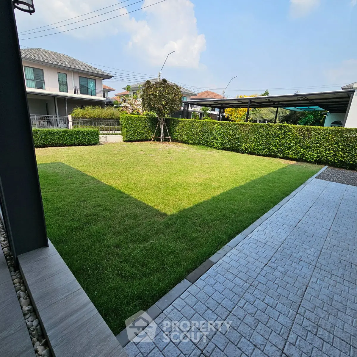 Spacious garden with lush green lawn and modern paving in a residential area.