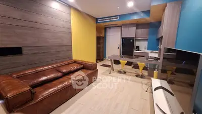 Modern living room with stylish kitchen and leather sofa in open layout apartment.
