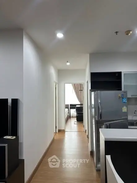 Modern apartment hallway leading to a cozy living room with sleek kitchen area.