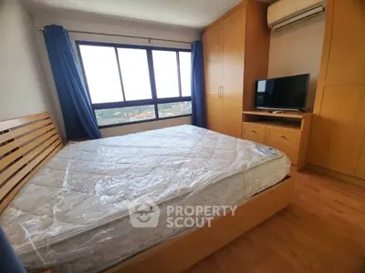 Spacious bedroom with large window and wooden furniture