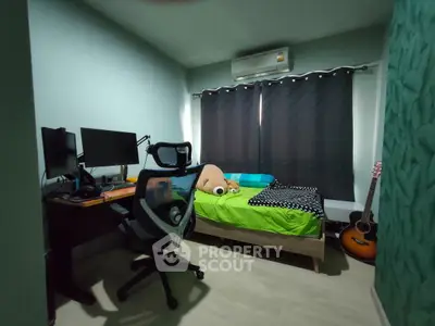 Cozy bedroom with modern desk setup and guitar, ideal for work and relaxation.