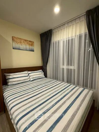 Cozy bedroom with modern decor and large window draped with elegant curtains.